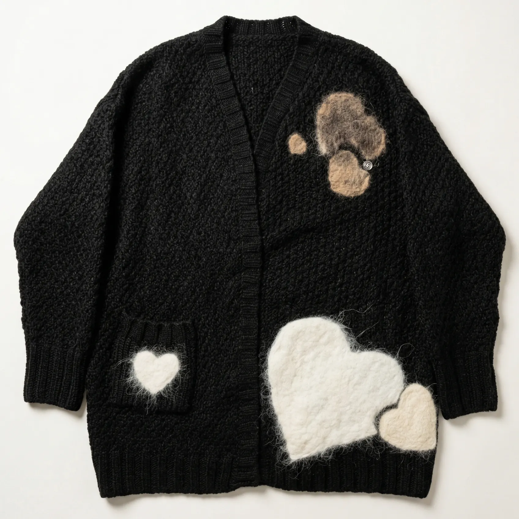 A black knitted cardigan featuring fuzzy felted patches, including a paw print design on the upper right chest and white heart shapes on the lower body and pocket.