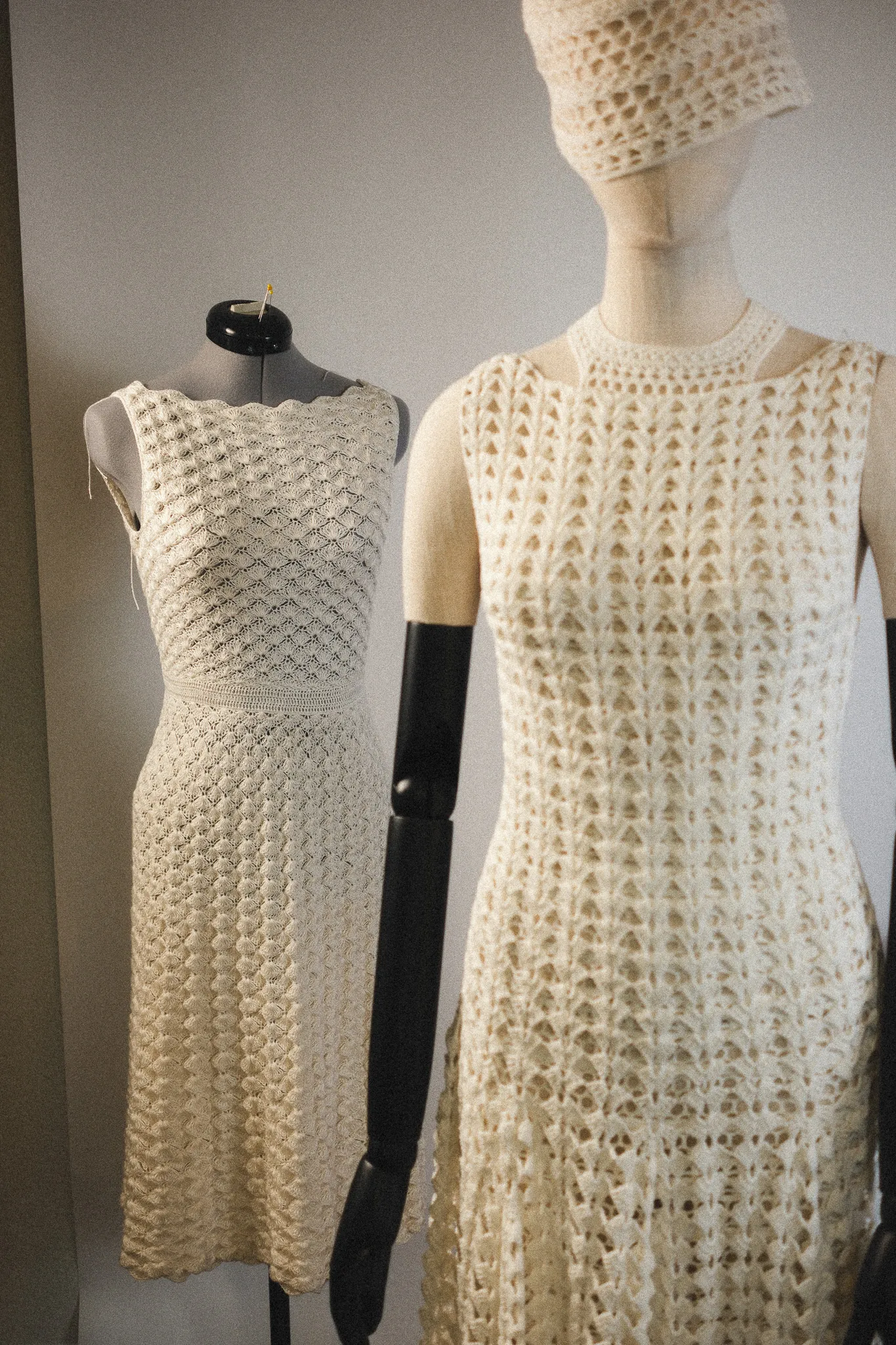 An atelier view of two cream, hand-sculpted crochet dresses on mannequins, showcasing the architectural precision and gravity-defying fit achieved through our signature hook technique.