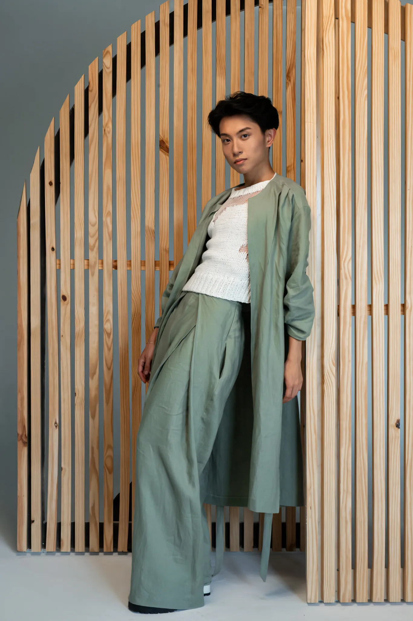 Model in Looking Friday soft olive Relaxed Linen Duster and high-waisted Linen Fold-In Pants over a white Distressed Knit Top.