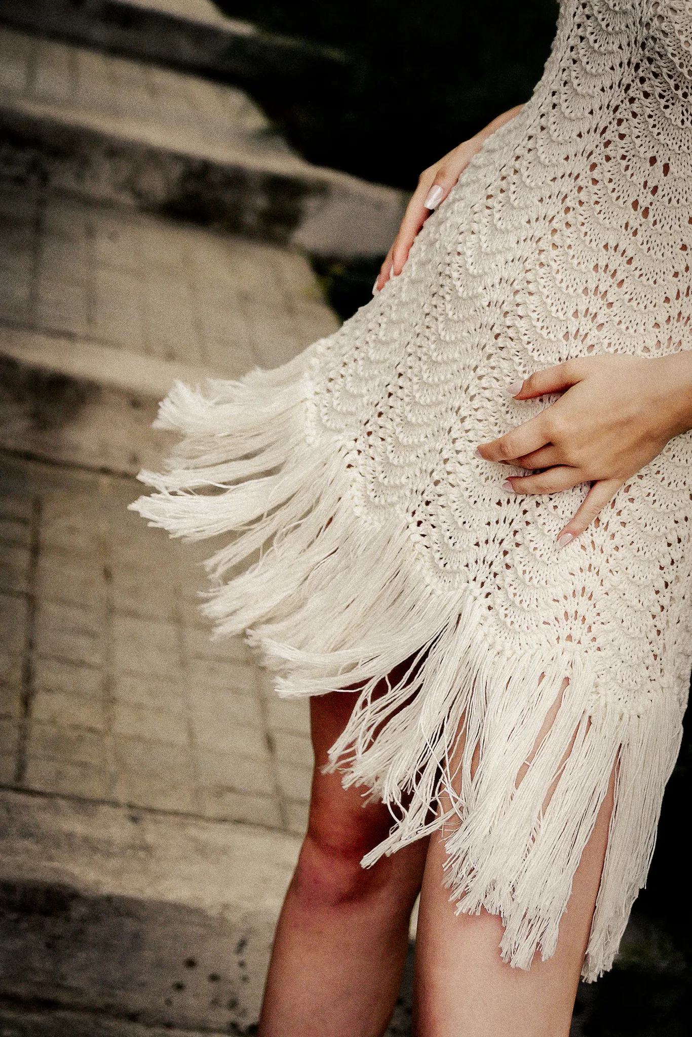 Detail photo of Looking Friday's Cyndi Dress, highlighting the organic cotton hand-knitted mini dress with a flowing fringe hem swishing outdoors