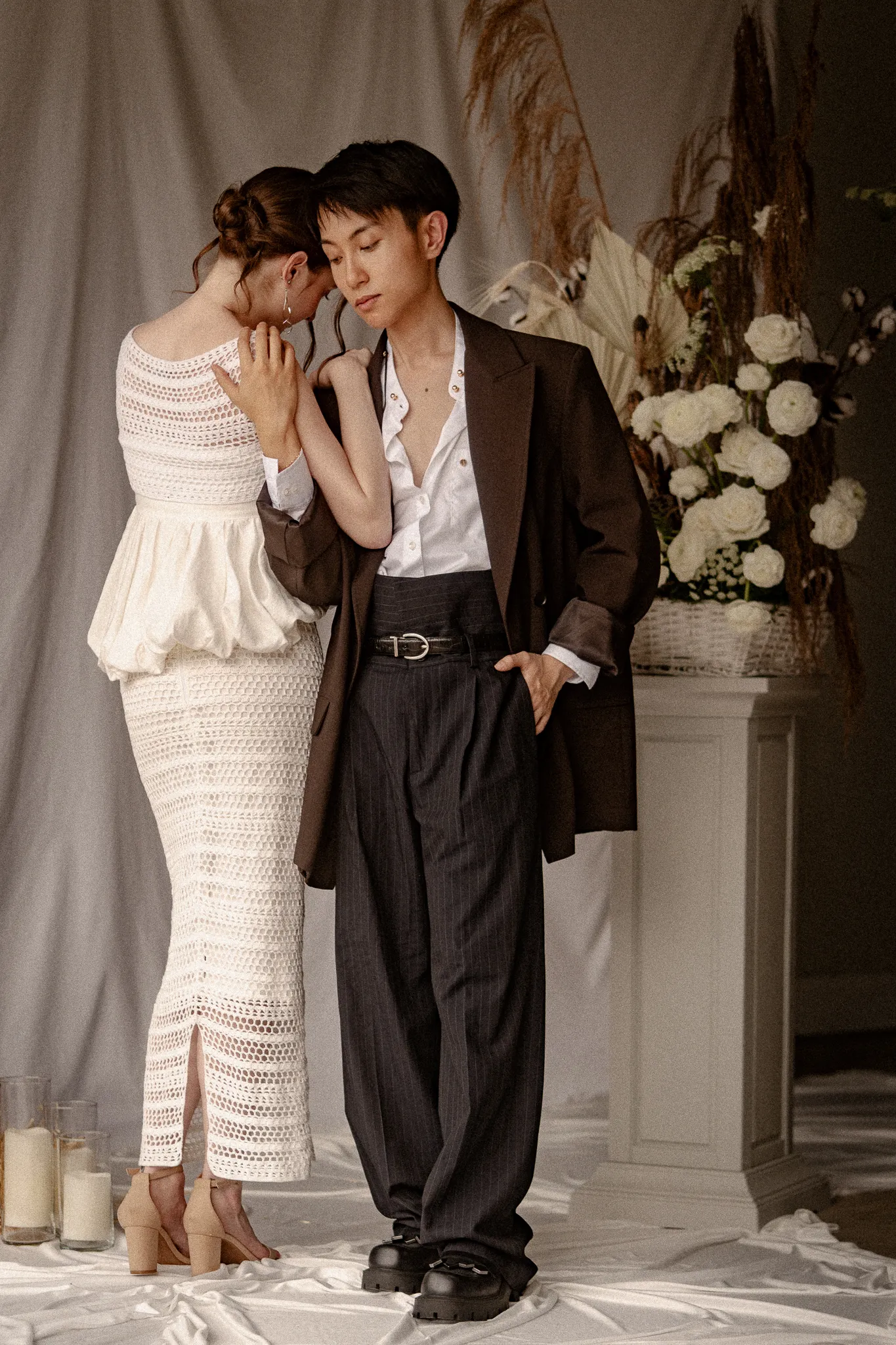 Editorial portrait of a couple embracing, showcasing Looking Friday's Grace Set featuring a structured linen peplum waist, short crochet coverup, and a fitted crochet column skirt with a back slit.