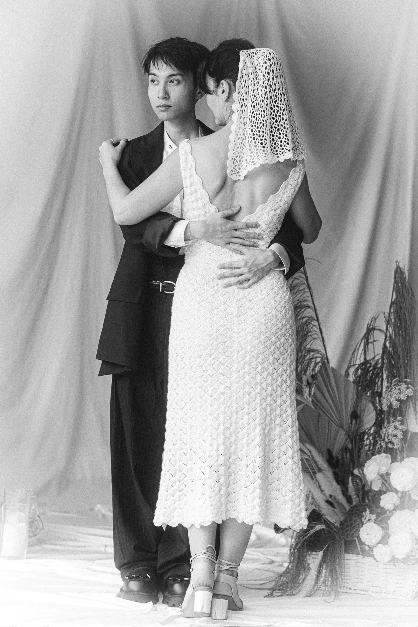 Couples editorial featuring the Katharine Dress by Looking Friday, an ankle-length silk crochet wedding dress with an open back and short crochet veil.