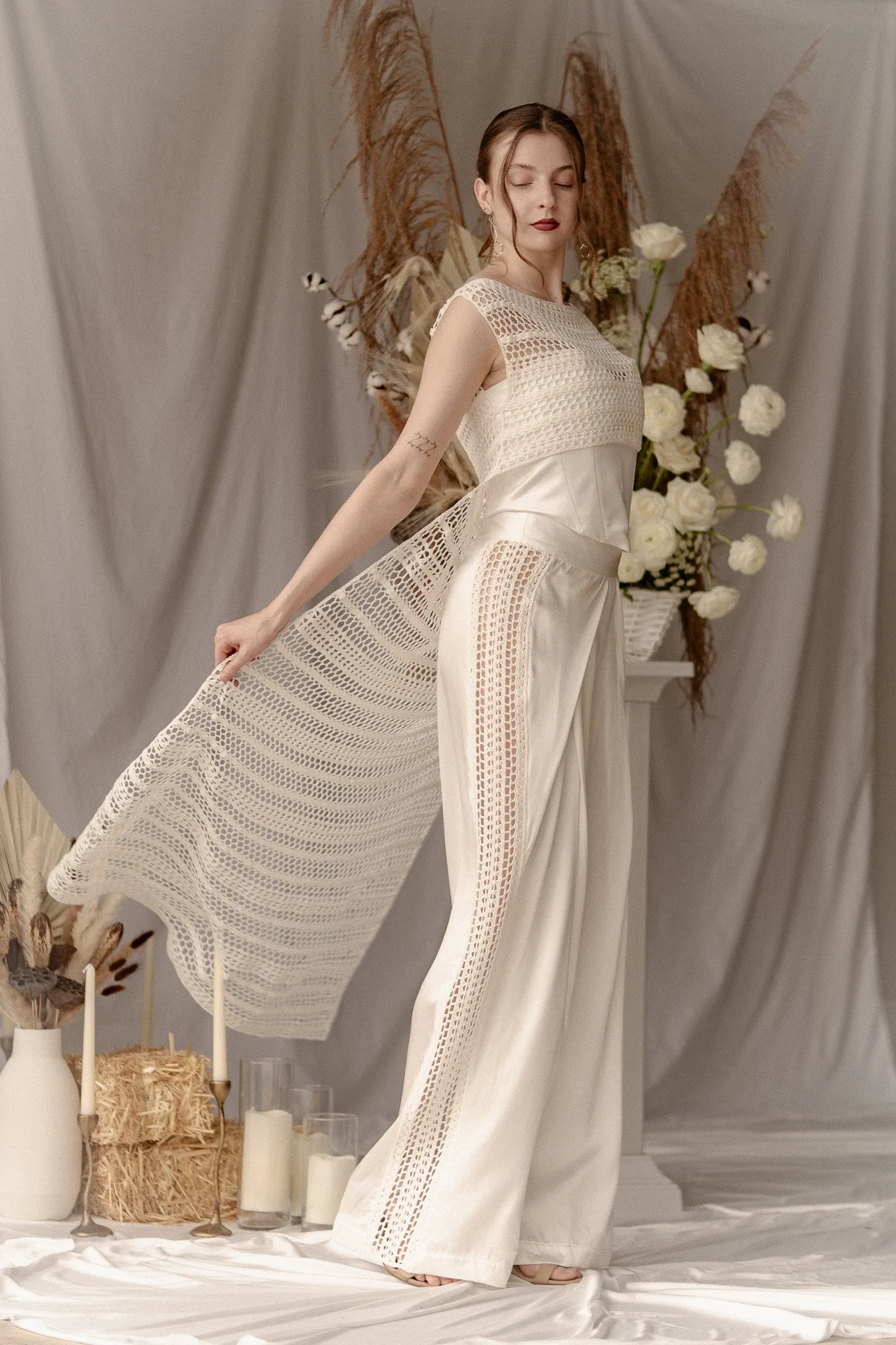 Full-length view of Looking Friday's Marlene Suit, featuring tailored organic cotton and pure silk wide-leg pants, hand-crocheted tuxedo side stripes, and an attached crocheted cape train in motion.